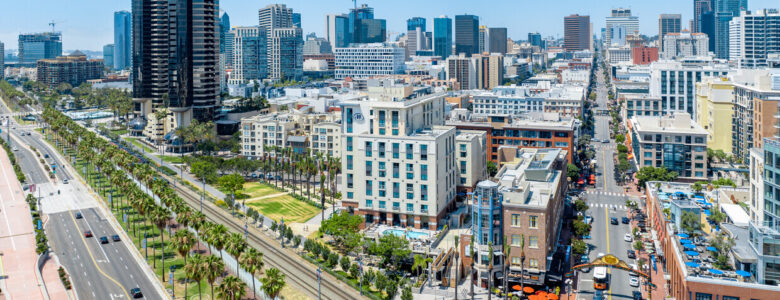 Professional downtown San Diego realtor discussing strategic SEO techniques in a modern office, with the city skyline in the background, enhancing online real estate visibility.